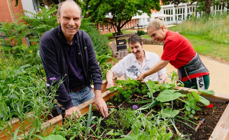 Zwei Herren arbeiten mit einer Betreuerin im Garten