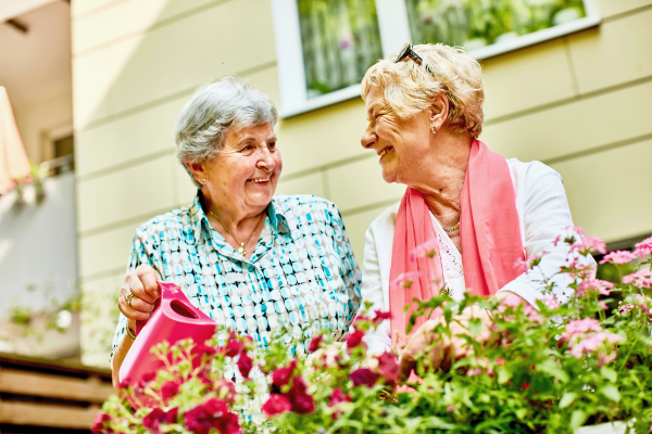 Zwei Omas gießen Blumen und freuen sich dabei